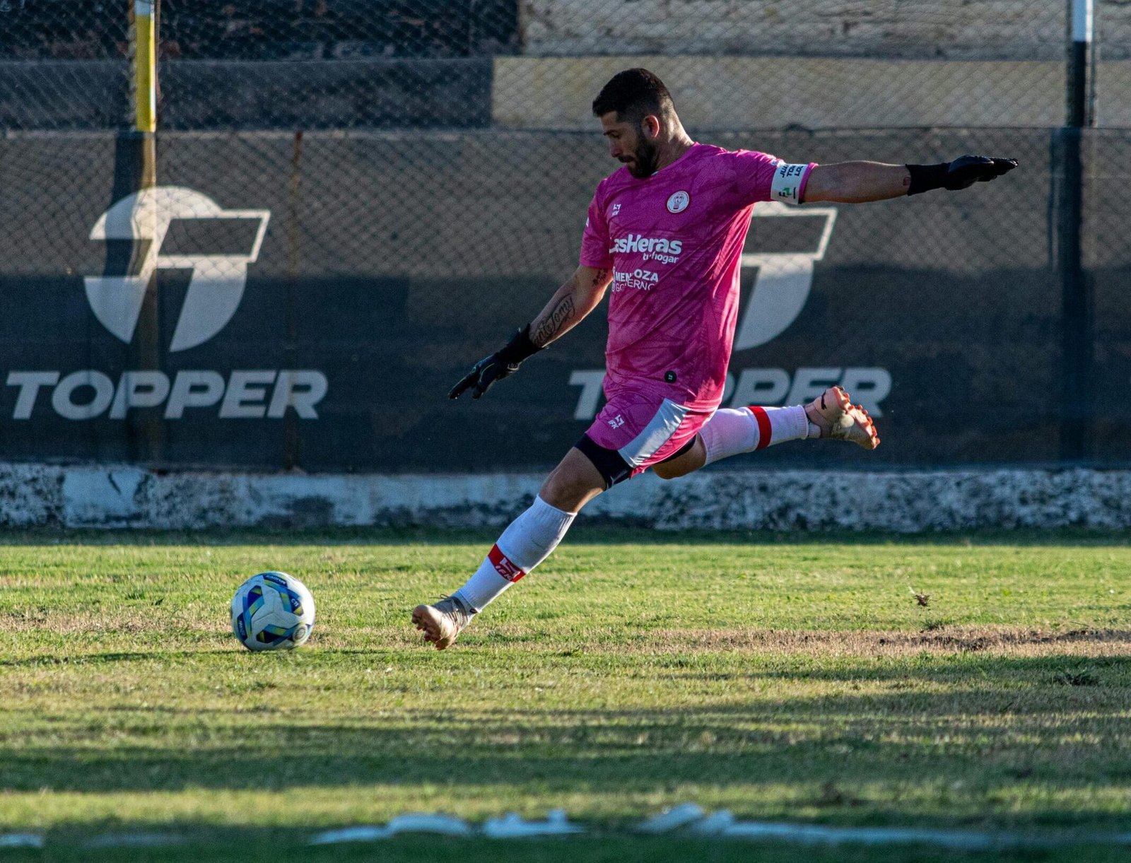 Dynamic shot of a soccer player kicking a ball on the field during a match.